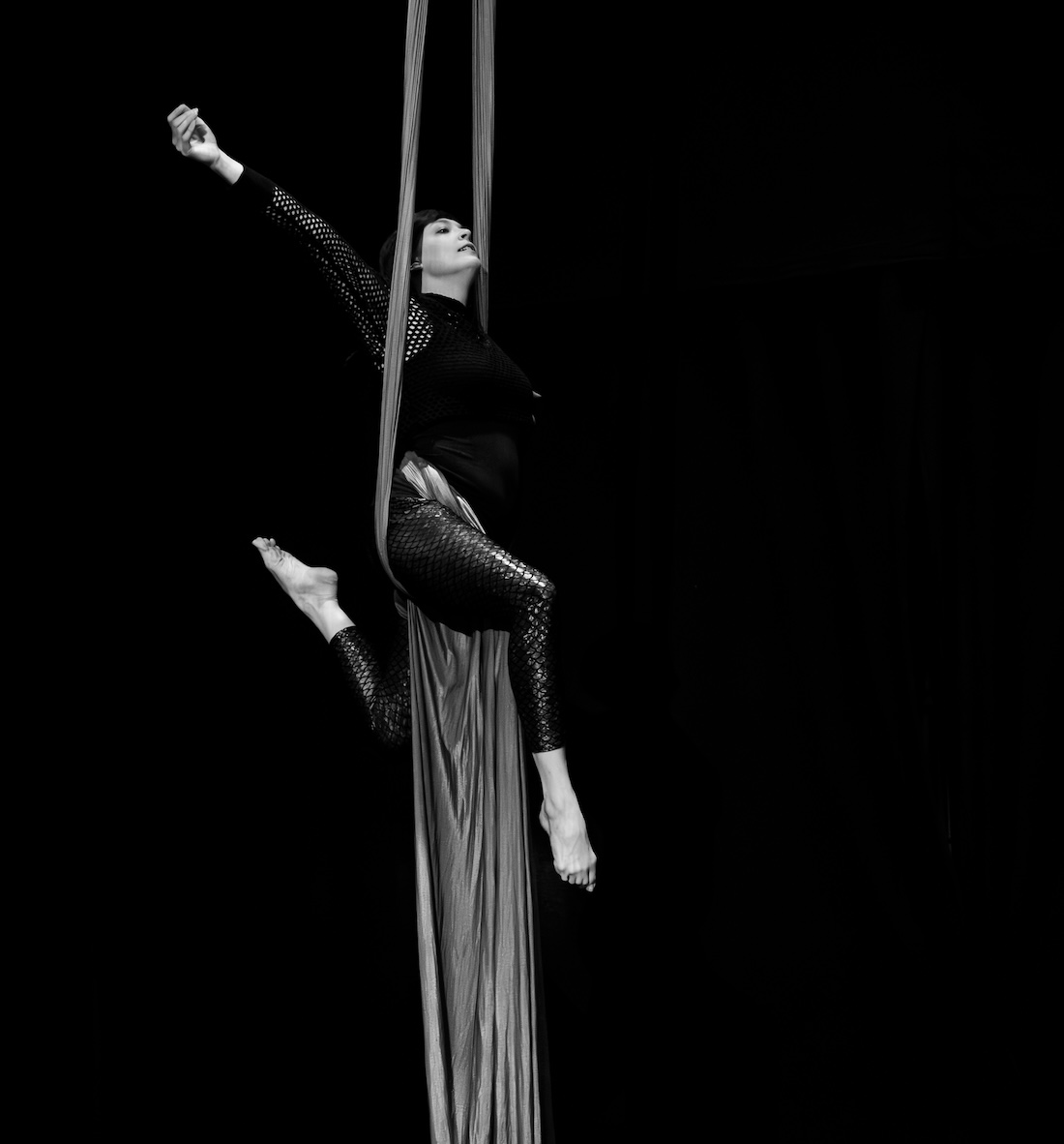 black and white photo of Sara striking a pose on aerial silks